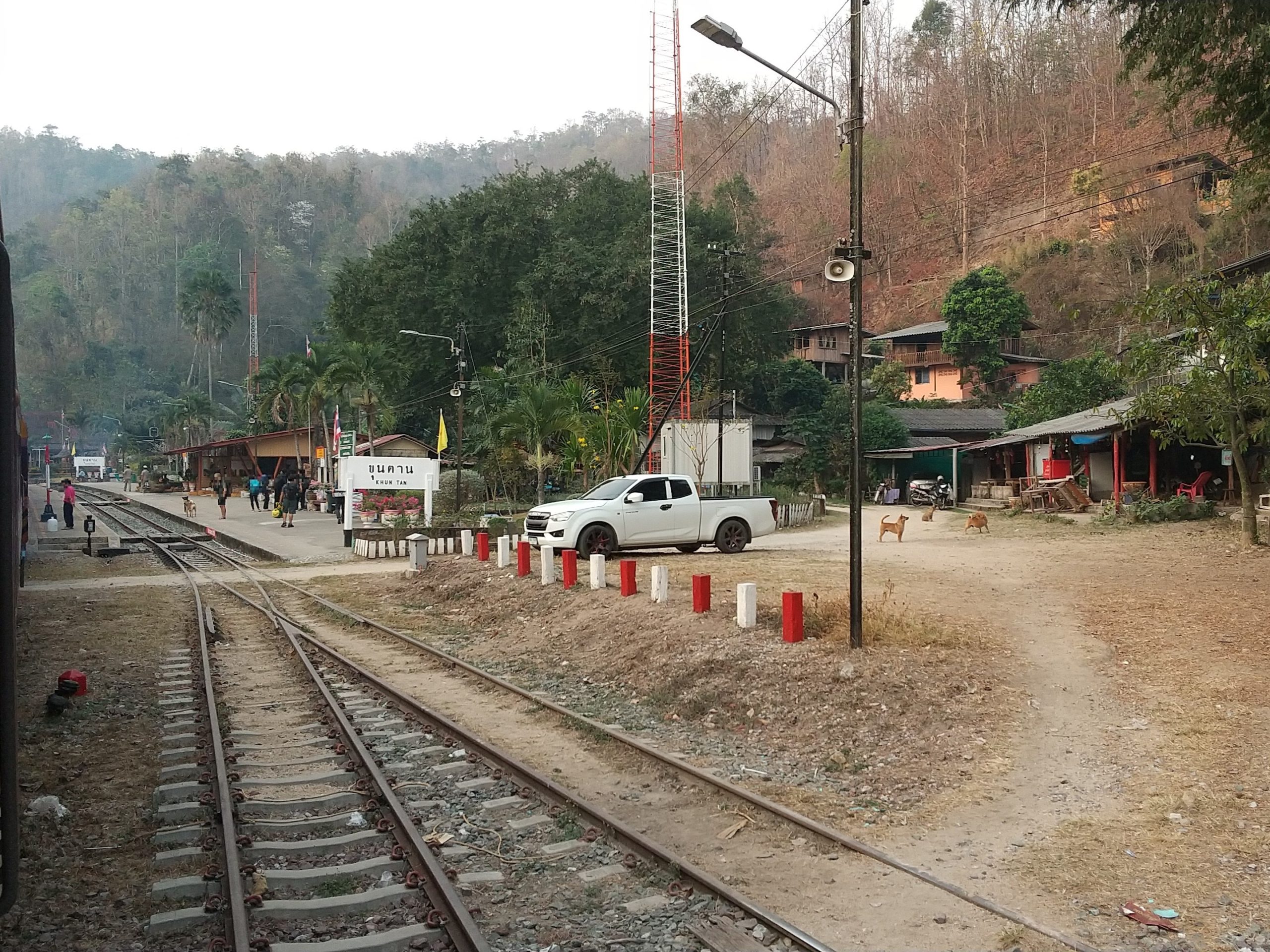 站牌、站台与沿坡房屋挨在一起,铁轨在前景分岔。