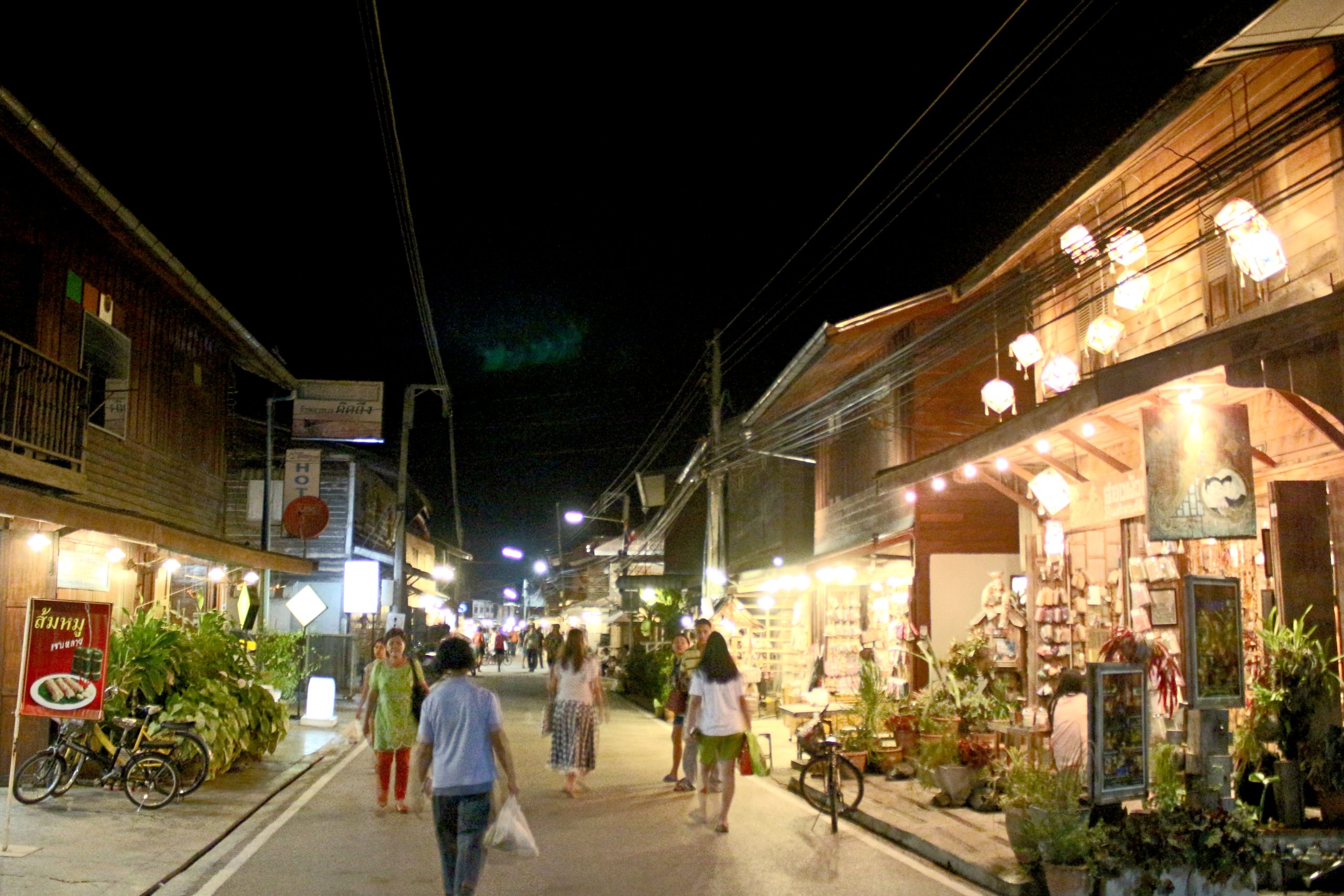 2014年清刊夜间街道,两侧是两层木屋、店铺灯光、自行车和步行的人