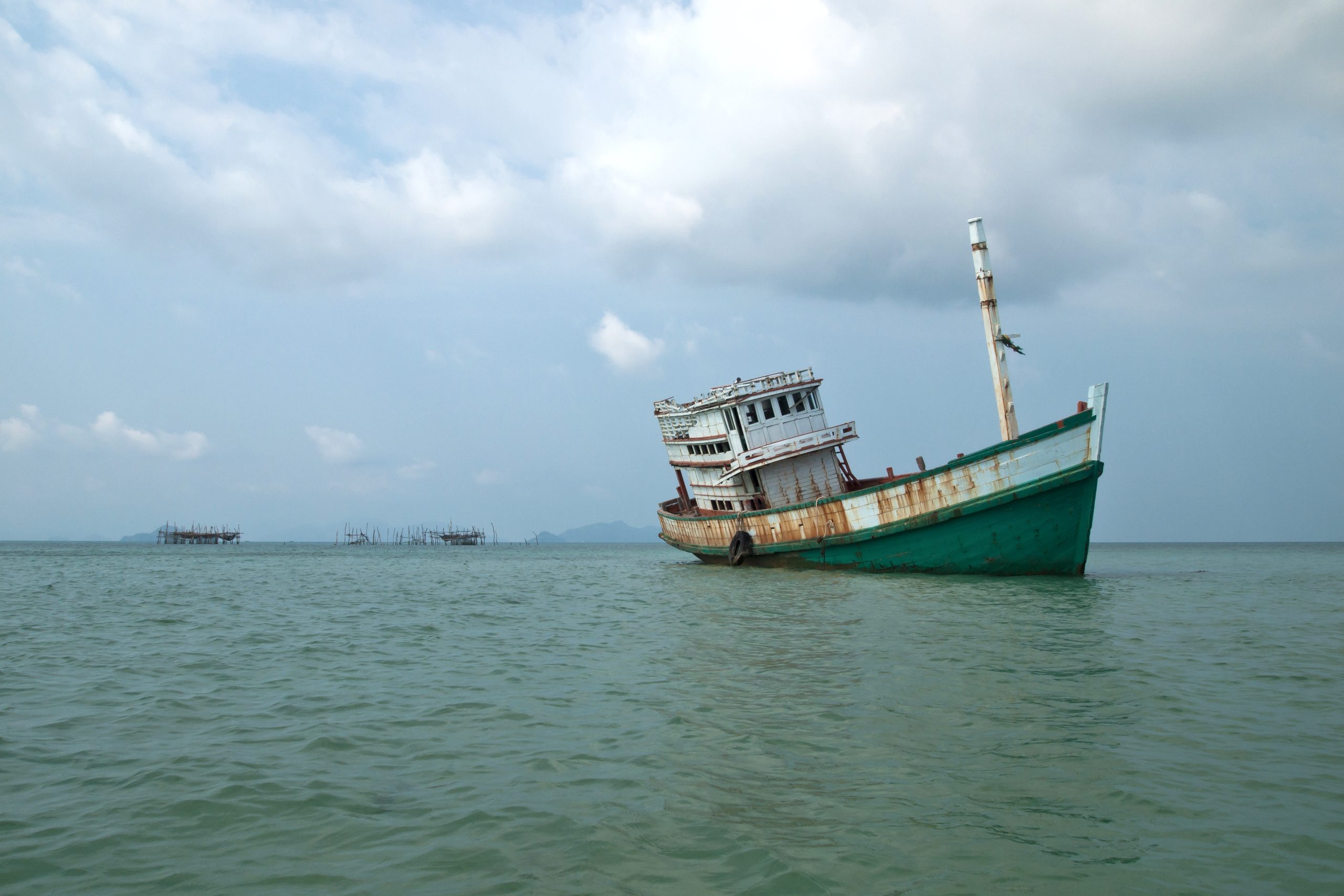 2010年阁玛岛浅水中的风化绿色木船和海上木桩