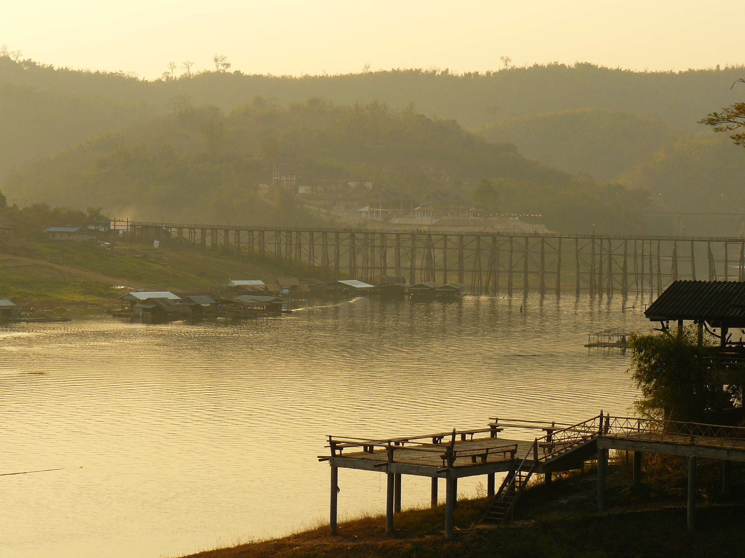 2011年桑卡拉布里孟桥远景,木桥横跨水面,两岸可见住屋。