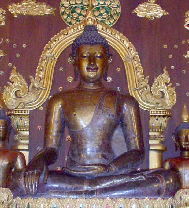 铜色Phra Chao Lan Thong坐像，右手垂膝左手置腿，红墙金色拱框