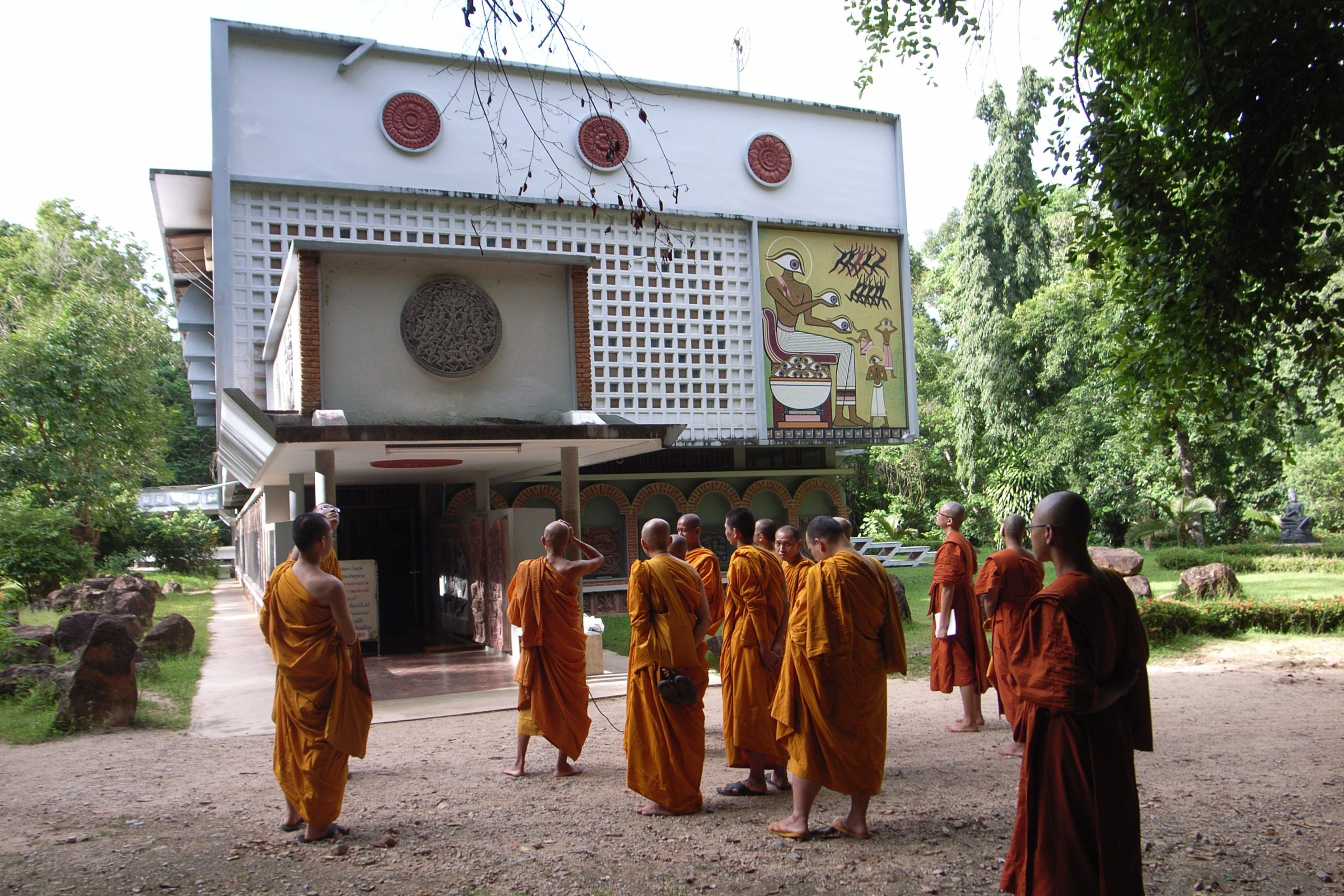 2009年柴亚Suan Mokkh:白墙前的僧人、红色圆盘、浮雕与黄底绘画