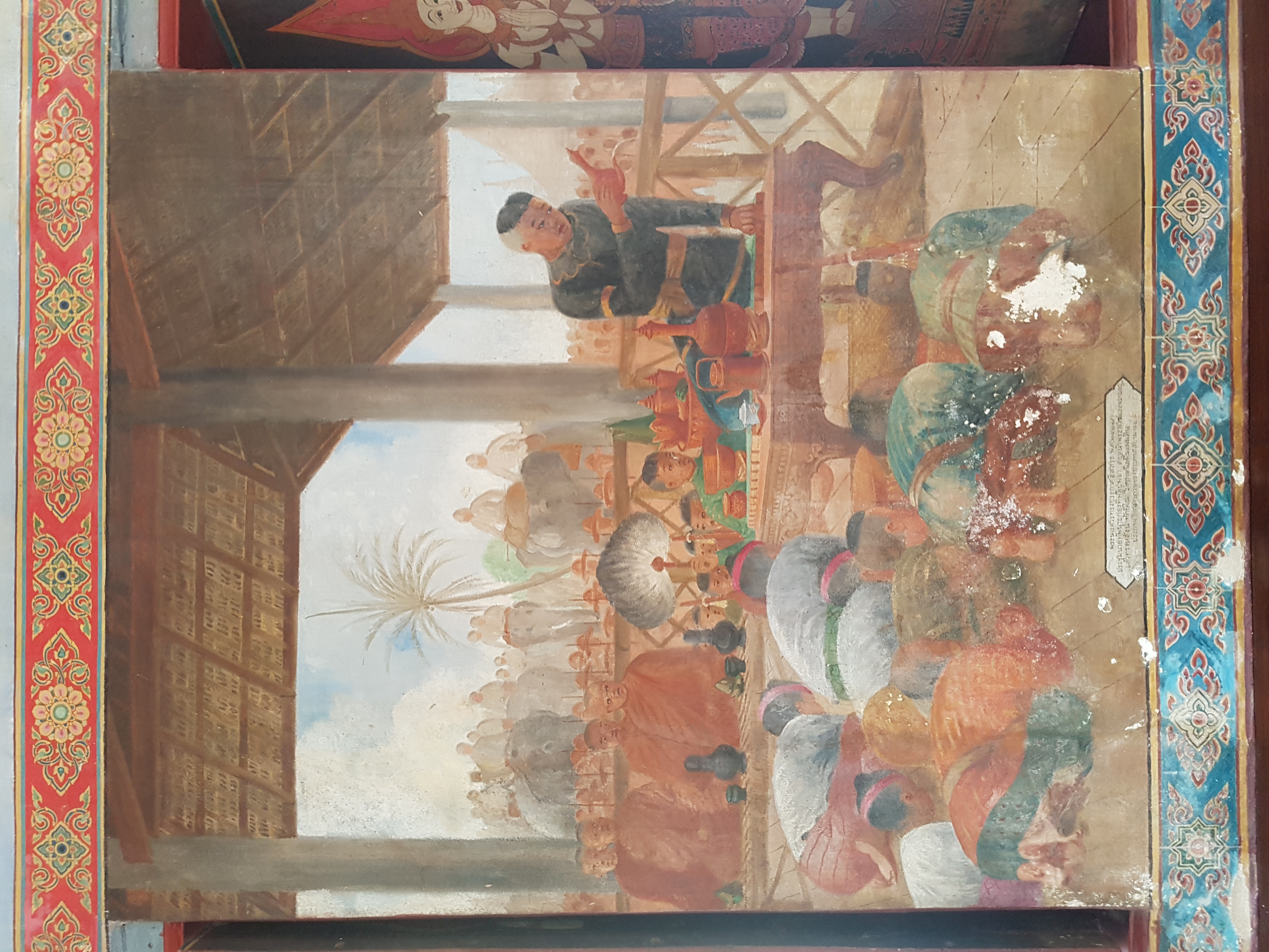 壁画中深色衣服男子将红色器物倾水，左边有僧人，前方有人俯身，屋外有骑象者，木柱与屋顶向远处延伸。