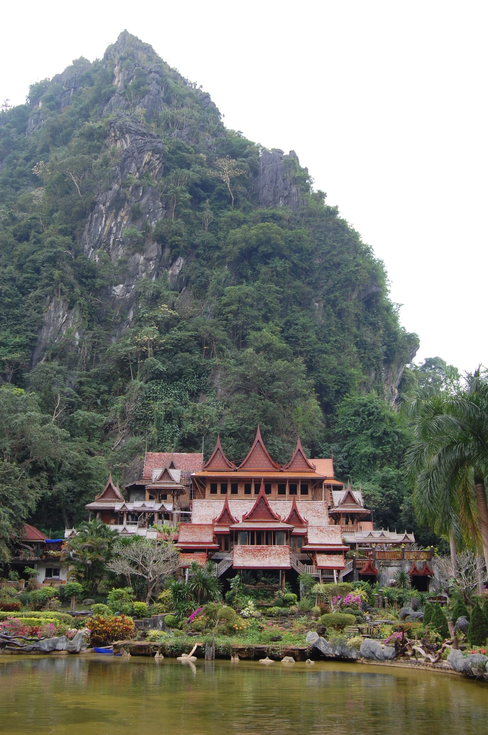 班莱Wat Tham Khao Wong,石灰岩山脚的多层木寺与前景池水