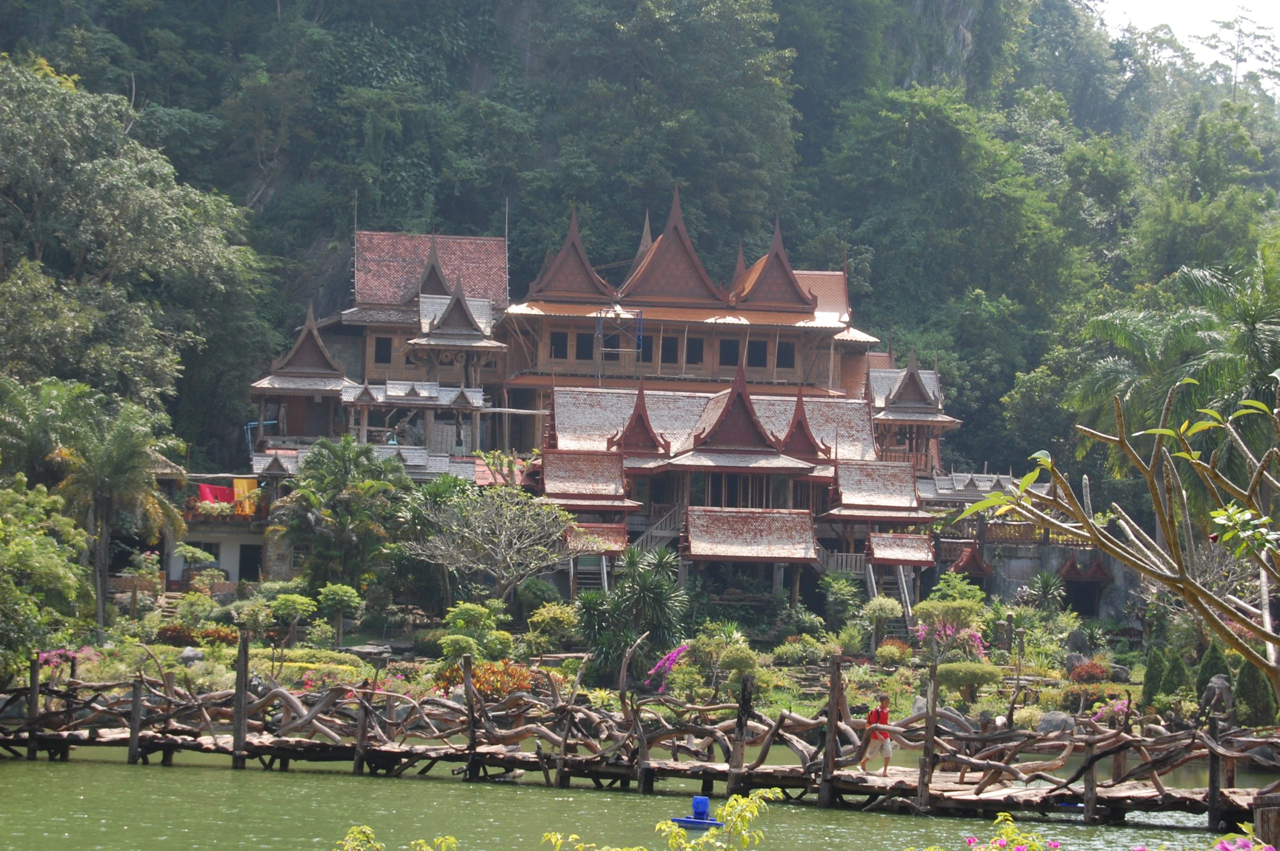 Wat Tham Khao Wong池上的枝形木桥,花园后方的层檐木楼